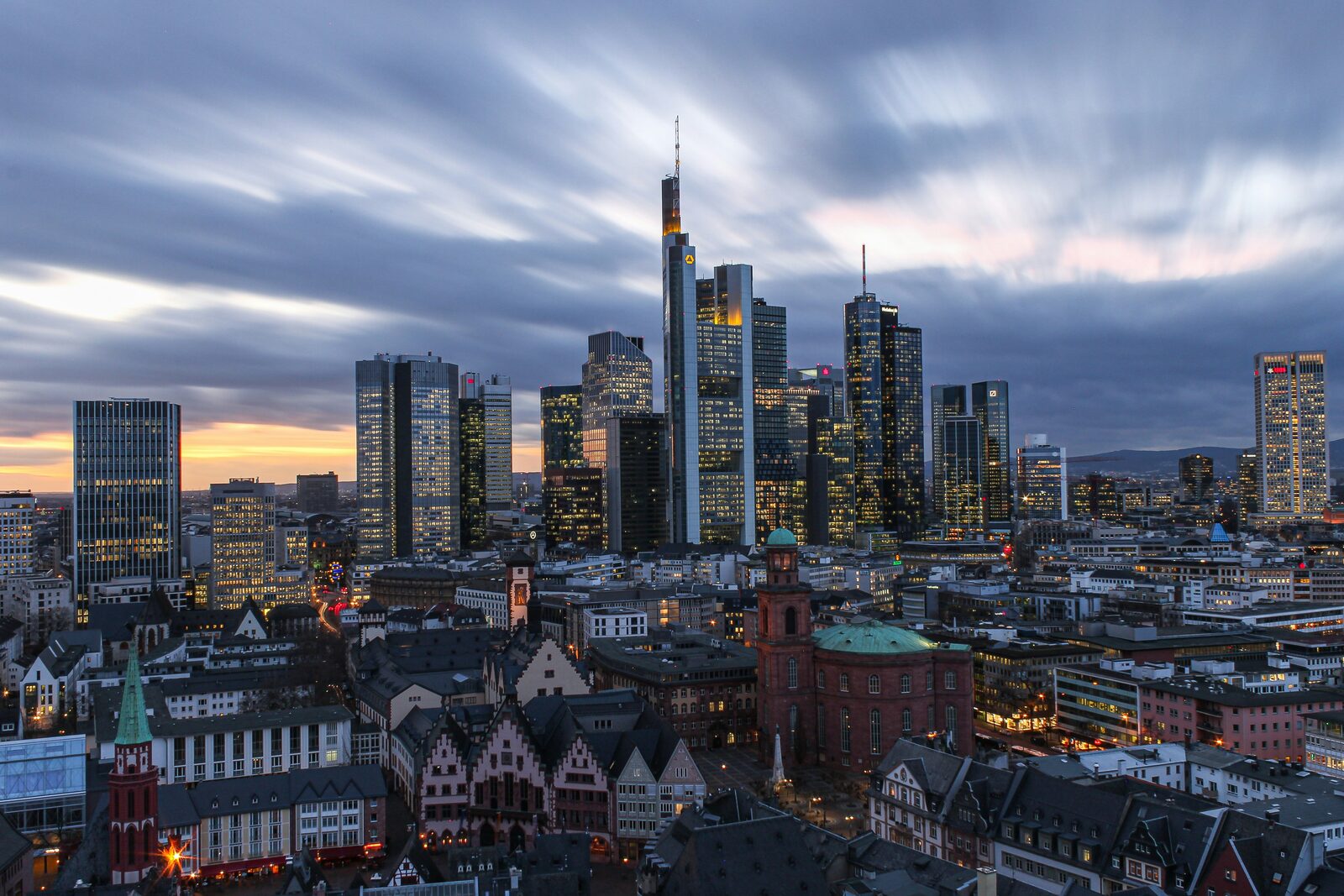 Die Frankfurter Bankenskyline in der Dämmerung, davor die Dächer der Altstadt.